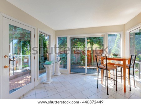 Light tones dining room interior with exit to back yard. Dining table set, tile floor and large windows.