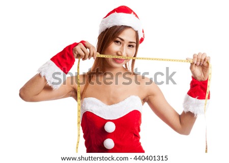 Asian Christmas girl in Santa Claus clothes diet with  measuring tape on gray background