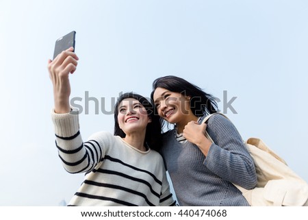 Two girls using mobile phone to take photo