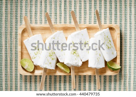 coconut ice pops ,coconut ice cream bars, with fresh green lime zest on wooden 
tray