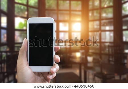 Man's hand shows mobile smartphone in vertical position and blurred background
