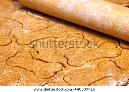 Homemade dog biscuit dough rolled out with bone-shaped cut-outs Royalty-Free Stock Photo #440589916