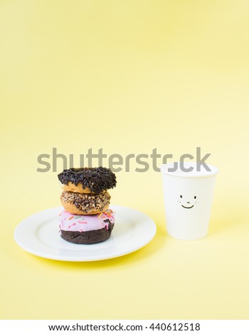 Coffee and donuts  on yellow background. Side light.
