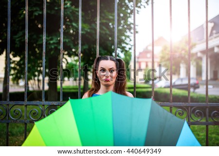 
Happy girl with colorful umbrella and red 
candy walking evening city. 
Joy,positive emotional facial attractive lady in a light summer dress