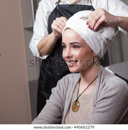 Barber girl preparing hair for haircut. Closeup picture of beautiful lady sitting in chair after having her hair washed in hairdressing saloon.