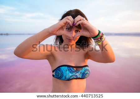 Pretty woman in a colorful lake making a heart with her hands