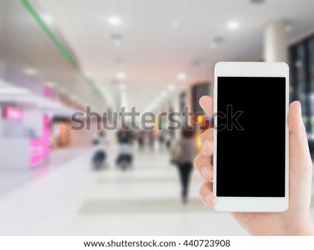 woman use mobile phone and blurred image of people walk in the airport terminal