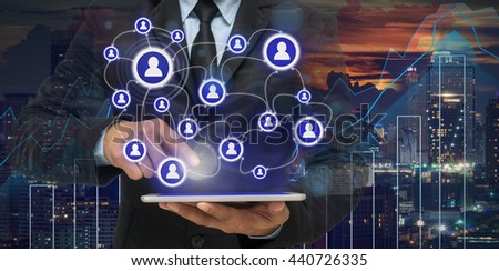 Businessman using the tablet for social connection with cityscape and financial graph on blurred building background, Business network concept