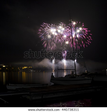 Ignis Brunensis pink and blue colored fireworks resembling aster flower reflecting on the water surface of dam. Long exposure night spatial photography using creative tilt effect by tilt-shift lens.