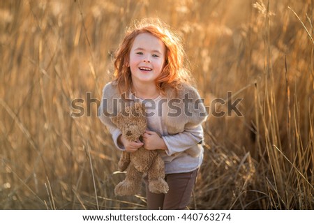 red-haired girl in the autumn grass field with a bouquet of ears of corn