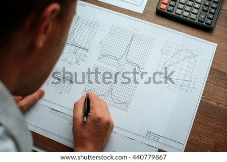 Man analyst working with documents, drawings, diagrams, graphics. With vignette.