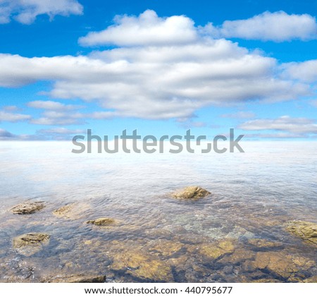 rocky entrance to the sea on a background of blue sky with clouds