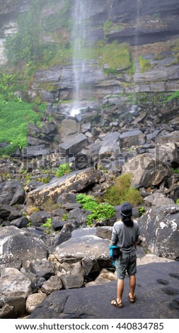 Travelers are walking on the rocks, a waterfall with Plant in the surrounding, bolaven plateau Laos