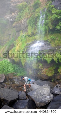 Travelers are walking on the rocks, a waterfall with Plant in the surrounding, bolaven plateau Laos