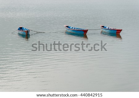 Three blue small boats on Phewa Lake in Pokhara, Nepal