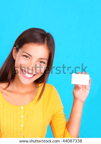 Beautiful young ethnic woman presenting a blank business card, on a bright blue background.