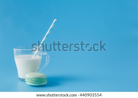 Glass of milk with french macaroon on blue background with copy space