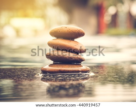 Stones pyramid with swimming pool blur background and sunlight. Photo of symbolizing zen concept and vintage style.