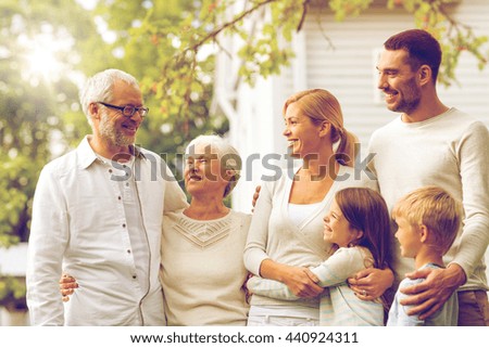 family, happiness, generation, home and people concept - happy family standing in front of house outdoors Royalty-Free Stock Photo #440924311
