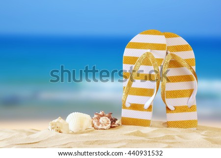 Image of tropical sandy beach, sea shells and flip flops. Summer concept