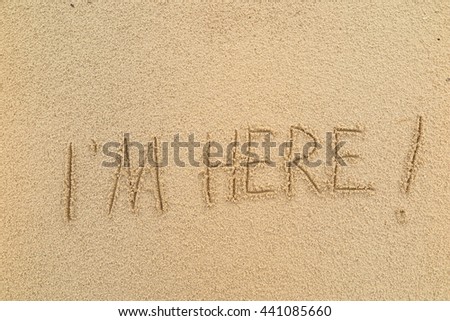 written words "I'M HERE!" on sand of beach