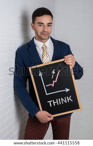 Man in a suit with a black board in his hands on a white background. Graph on blackboard and motivational text "THINK"