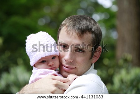 Close portrait of a loving father hugging little daughter in pink knitted cap outdoor