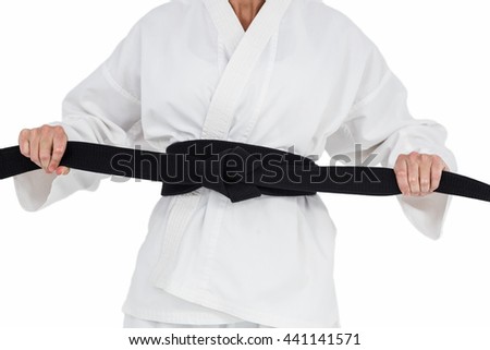 Female athlete tightening her judo belt on white background
