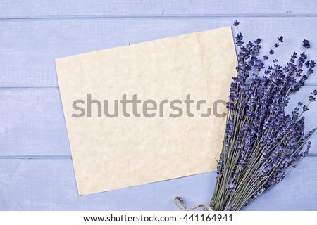 Overhead view of a bundle of dried lavender flowers over a blue wood table top with an old piece of paper with copy space.