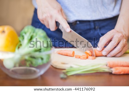 hands slicing carrot on the cutting board, closeup