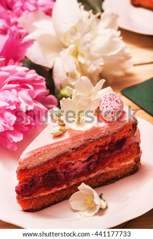 Food, food styling, cooking. Slice of pink cake with small white flowers and peonies