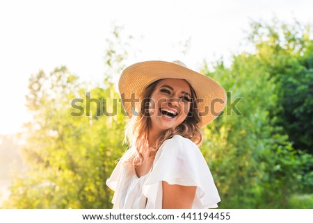 Laughing young woman enjoying her time outside in park with sunset in background. Royalty-Free Stock Photo #441194455