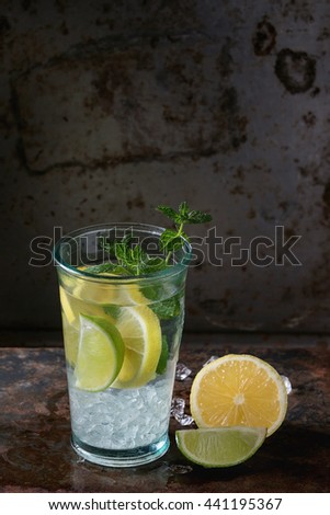 Homemade lemon and lime lemonade, served in glass  with ice and fresh mint, over dark iron rusty background. With space for text