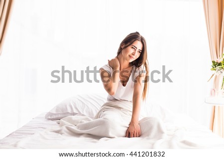 Tired sleepy woman waking up and yawning with a stretch while sitting in bed isolated on white background
