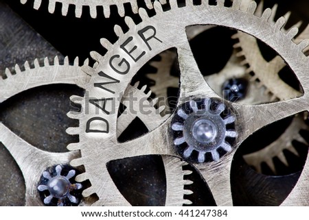 Macro photo of tooth wheel mechanism with DANGER concept letters