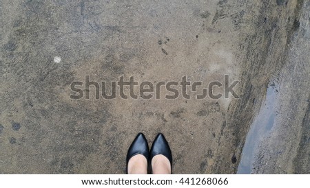 Woman's high heels on wet cement floor with copy space