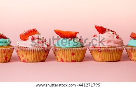 Closeup photo of colorful cupcakes with sprinkles and berries on top