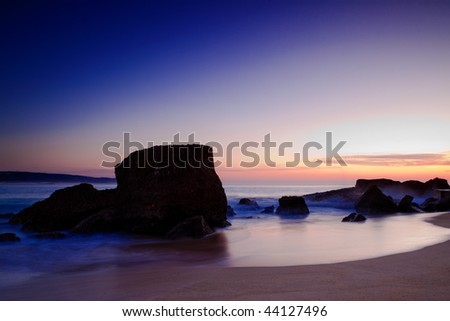 Landscape picture of rocks on the beach at sunset