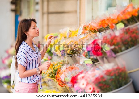 Beautiful young woman with long hair selecting fresh flowers at european market