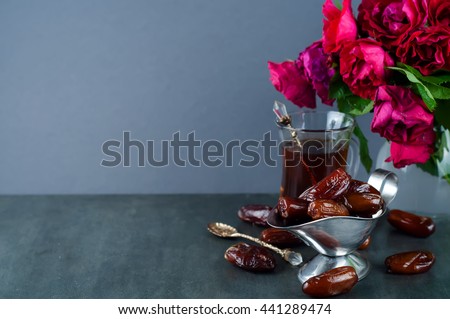 Traditional arabic tea set and dried dates. roses in the background