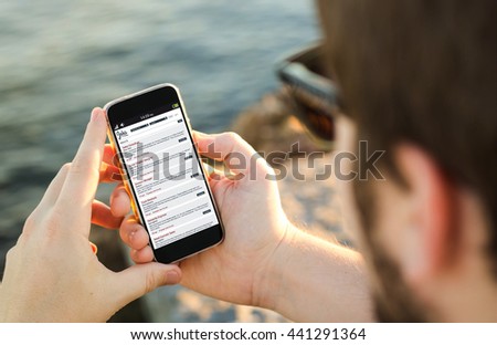 man on the coast using his smartphone looking for a job. All screen graphics are made up.
