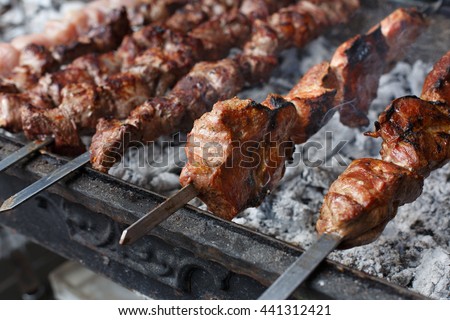 Grilled shish kebab on metal skewer, closeup. Roasted meat cooked at barbecue. BBQ fresh beef chop slices. Traditional eastern dish. Grill on charcoal and flame, picnic, street food