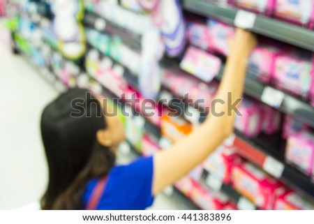 Blurred image of a woman with a shopping in the supermarket store.
