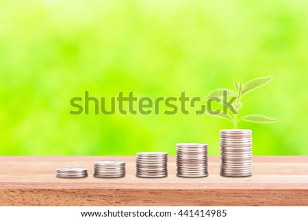 business growth chart by coins stack and shoots on top chart on table top on blur green nature background