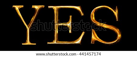 Wooden letters in gold on black background spelling YES