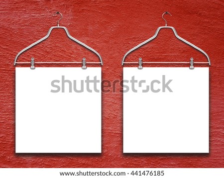 Close-up of two square blank frames hanged by clothes hanger against red rough concrete wall background