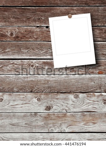 Close-up of one square blank instant photo frame with pin on brown wooden boards background
