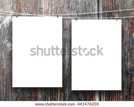Close-up of two blank frames hanged by pegs against dark wooden background