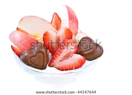 Fresh heart shaped strawberries and apple pieces with chocolates isolated on white background