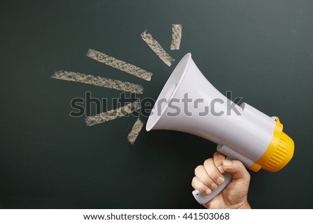 man holding megaphone in front of blackboard